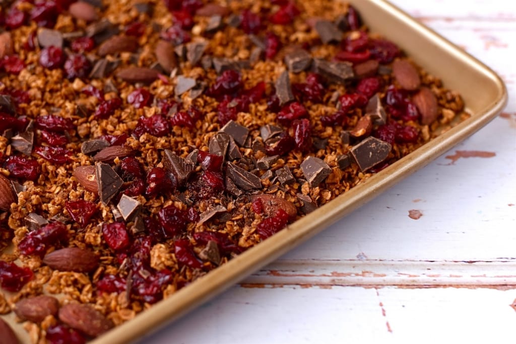 A tray of granola showing chunks of chocolate and dried cranberries.