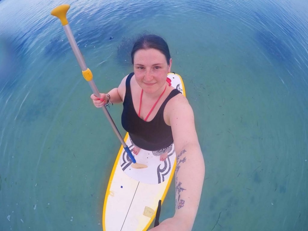 A woman taking a selfie while Stand up paddle boarding.