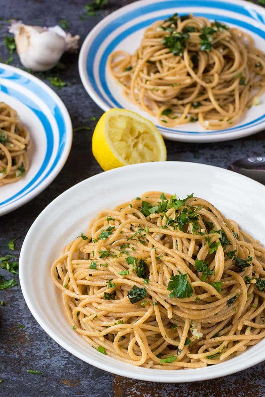 plates of cooked spaghetti topped with herbs.