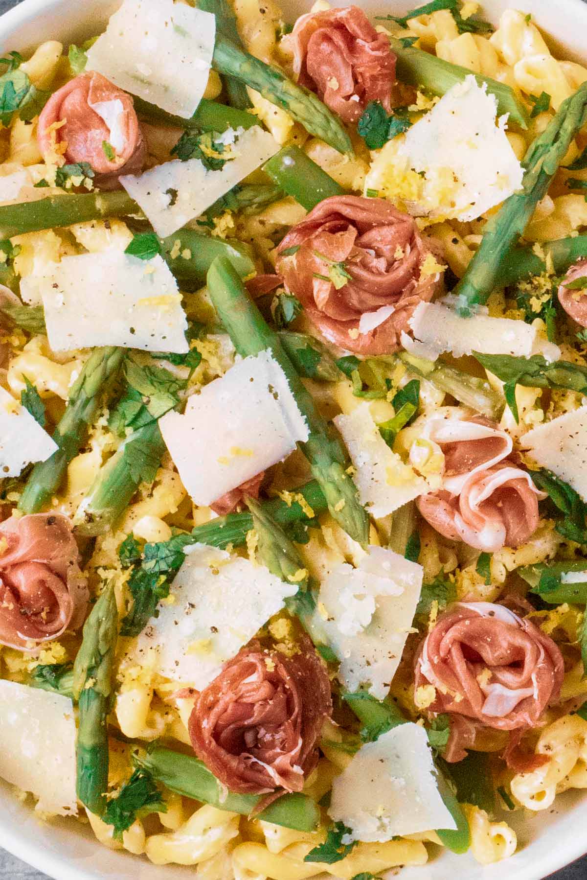 Cooked asparagus, pasta and prosciutto roses.