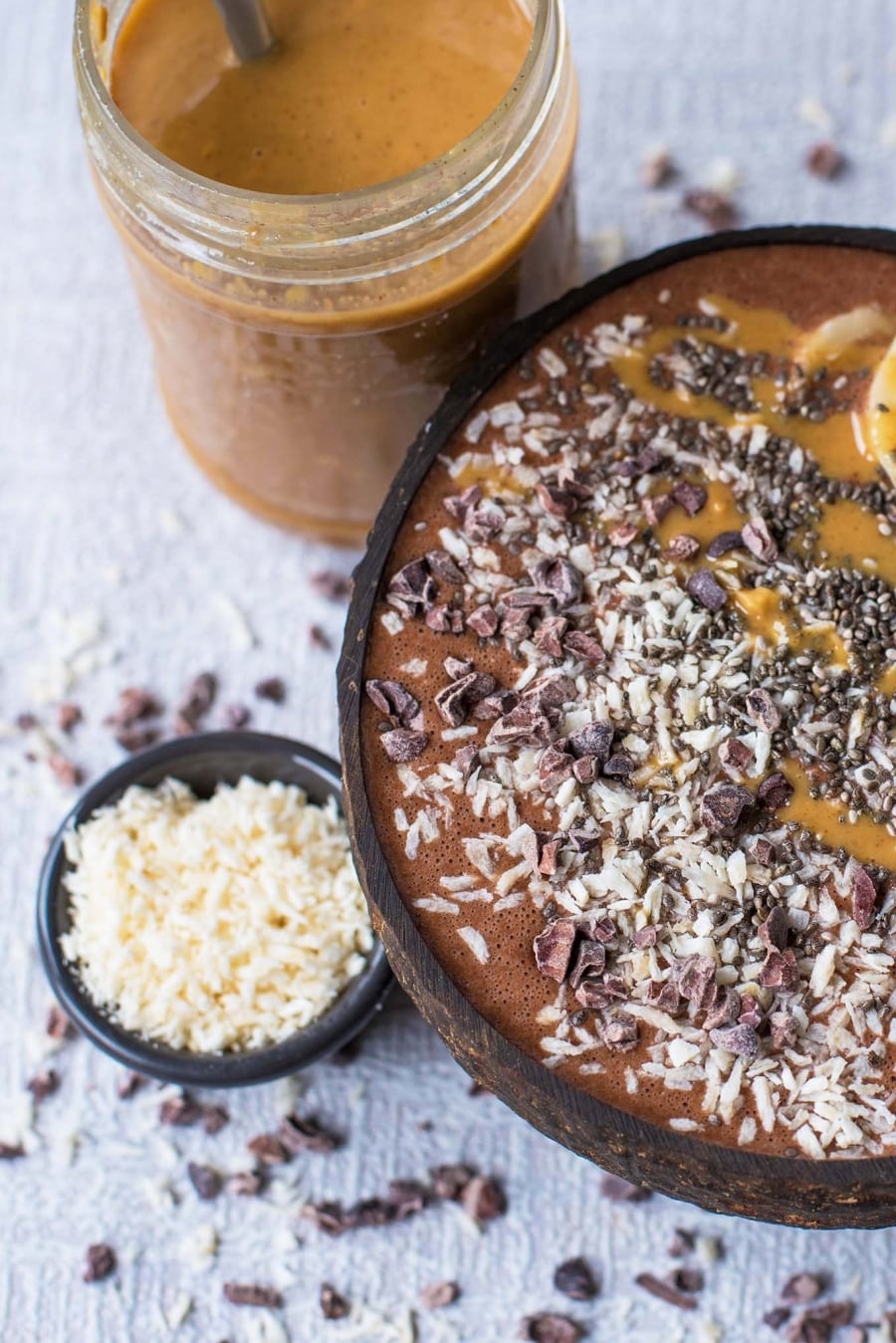 chocolate and coconut topped smoothie bowl and a jar of peanut butter.