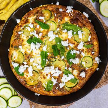 Courgette mint and feta frittata in a pan on a burlap mat.