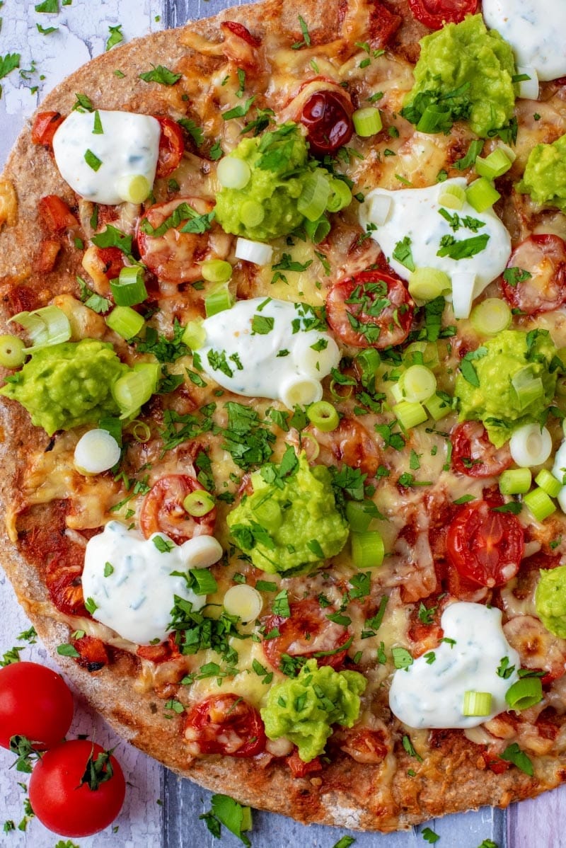 A pizza with guacamole and sour cream on it.