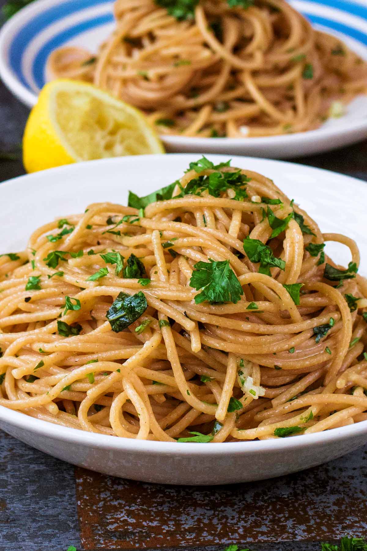 Plates of cooked spaghetti topped with herbs.