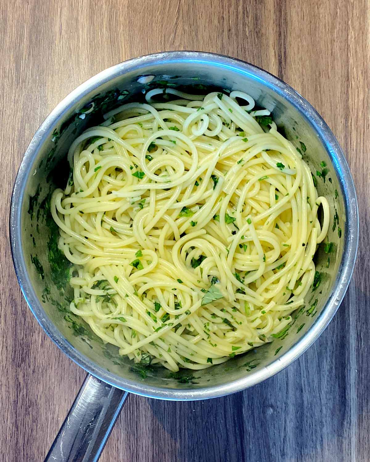 Cooked spaghetti with chopped herbs mixed into it.