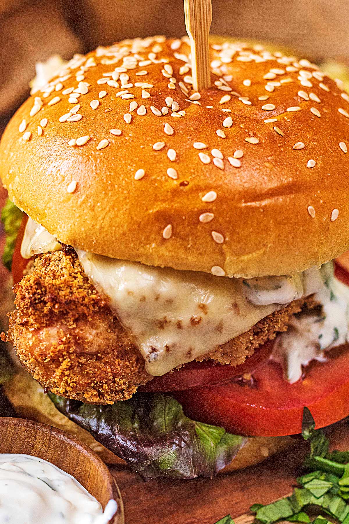 Breaded chicken topped with cheese in a sesame seed brioche bun with lettuce and tomato