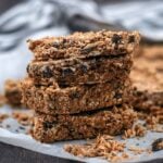 Four Chocolate Peanut Butter Oat Bars surrounded by crumbs on a wooden surface.