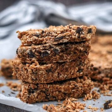 A stack of four oat bars on a sheet of baking paper.