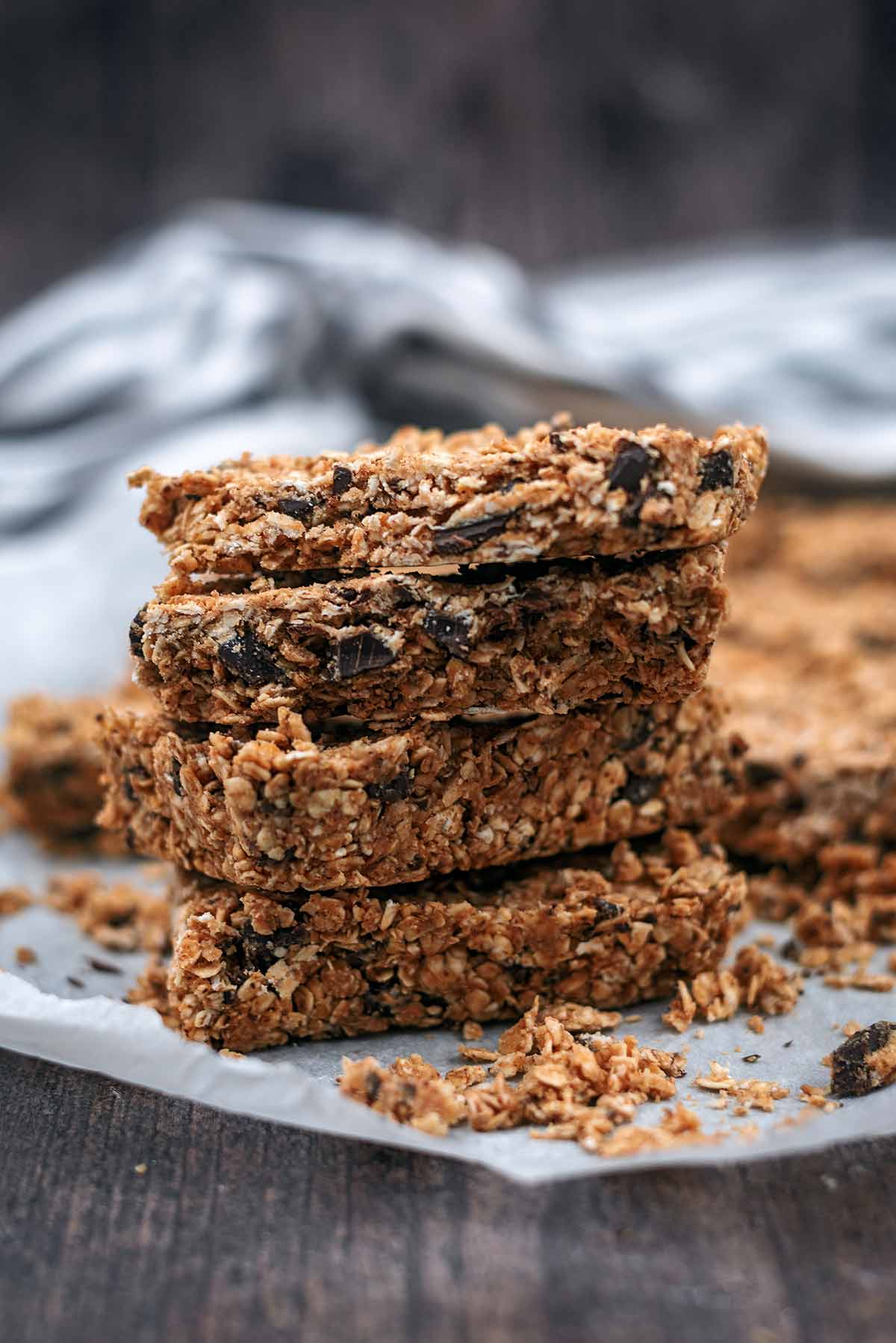 A stack of four oat bars on a sheet of baking paper.