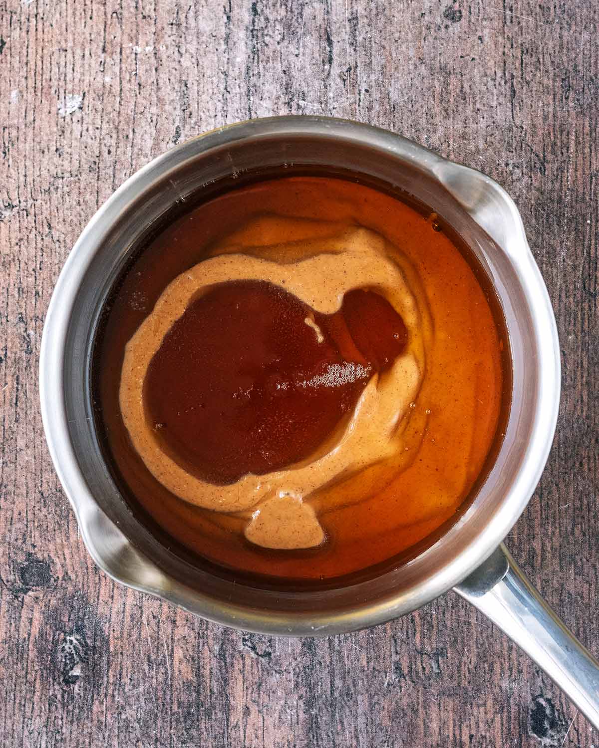 A small saucepan containing peanut butter and maple syrup.