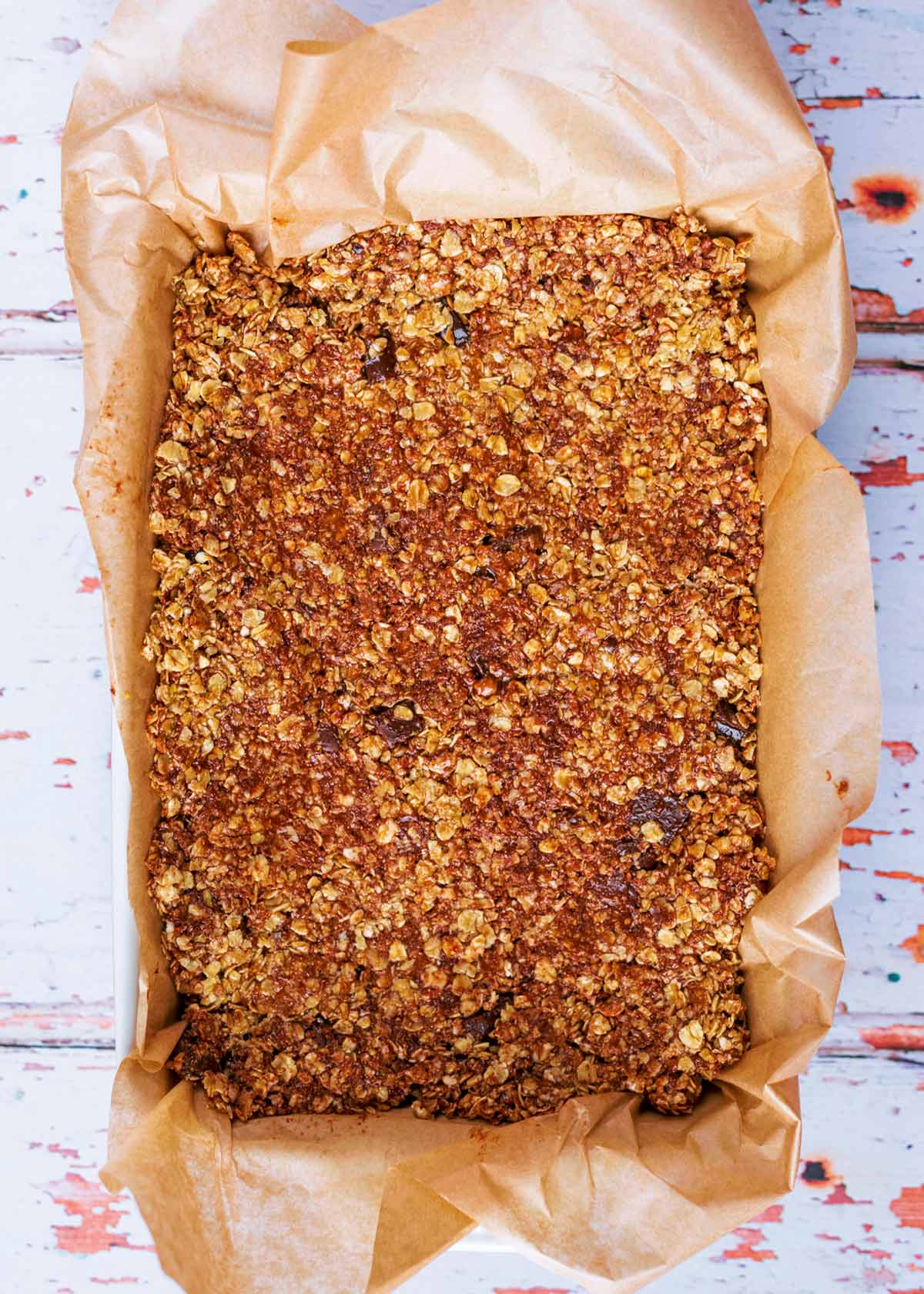 A lined baking dish with an oat and chocolate mix pressed into it.