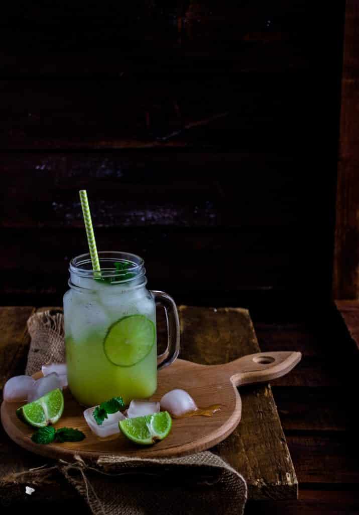 A green iced drink in a mason jar sat on a wooden serving board