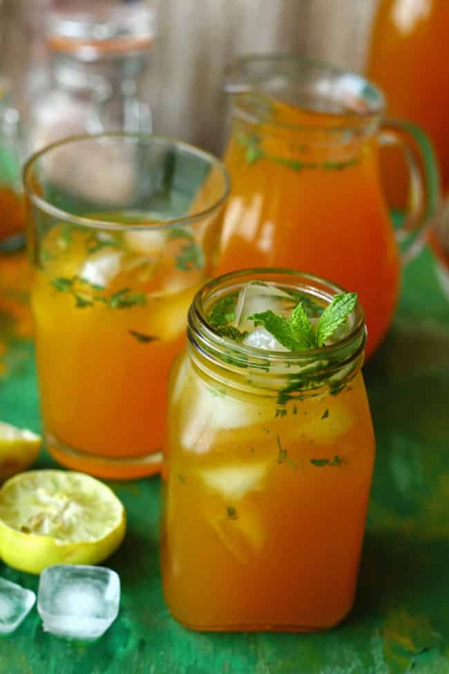 A dark orange drink in a jar with ice and mint leaves