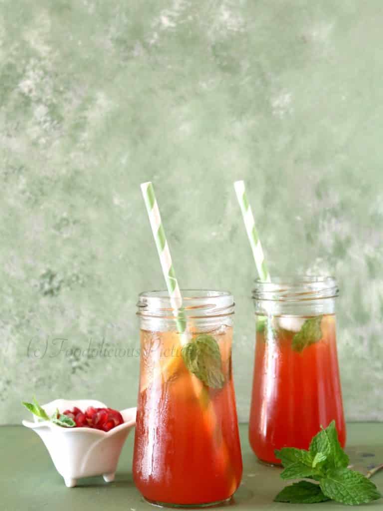 Two tall jars containing a red coloured drink with slices of lemon and mint leaves