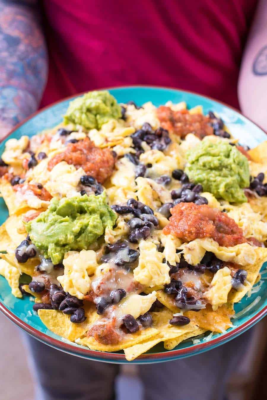 A plate of Nachos being held by someone.