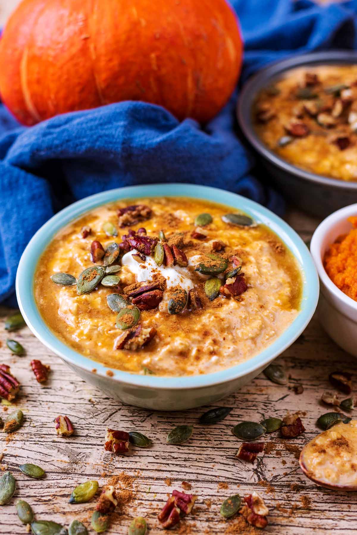 Overnight oats in a bowl with a whole pumpkin in the background.