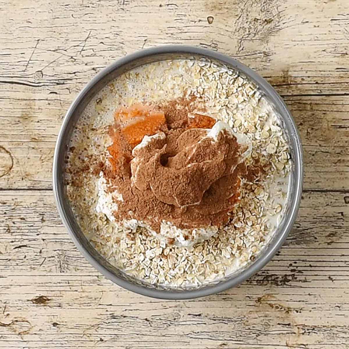 A bowl of oats, milk, yogurt, pumpkin puree and spices.