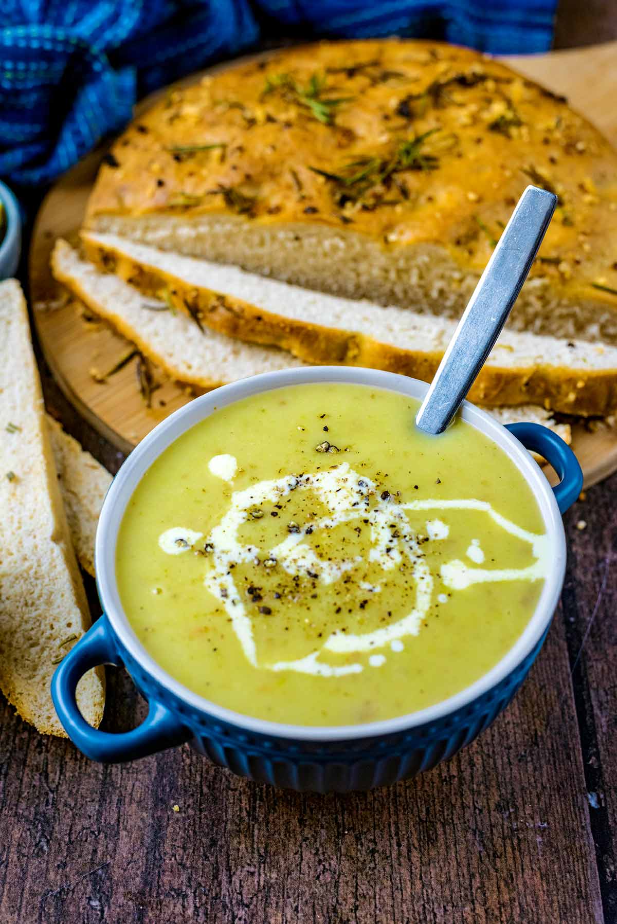 A bowl of leek and potato soup in front of some sliced bread.