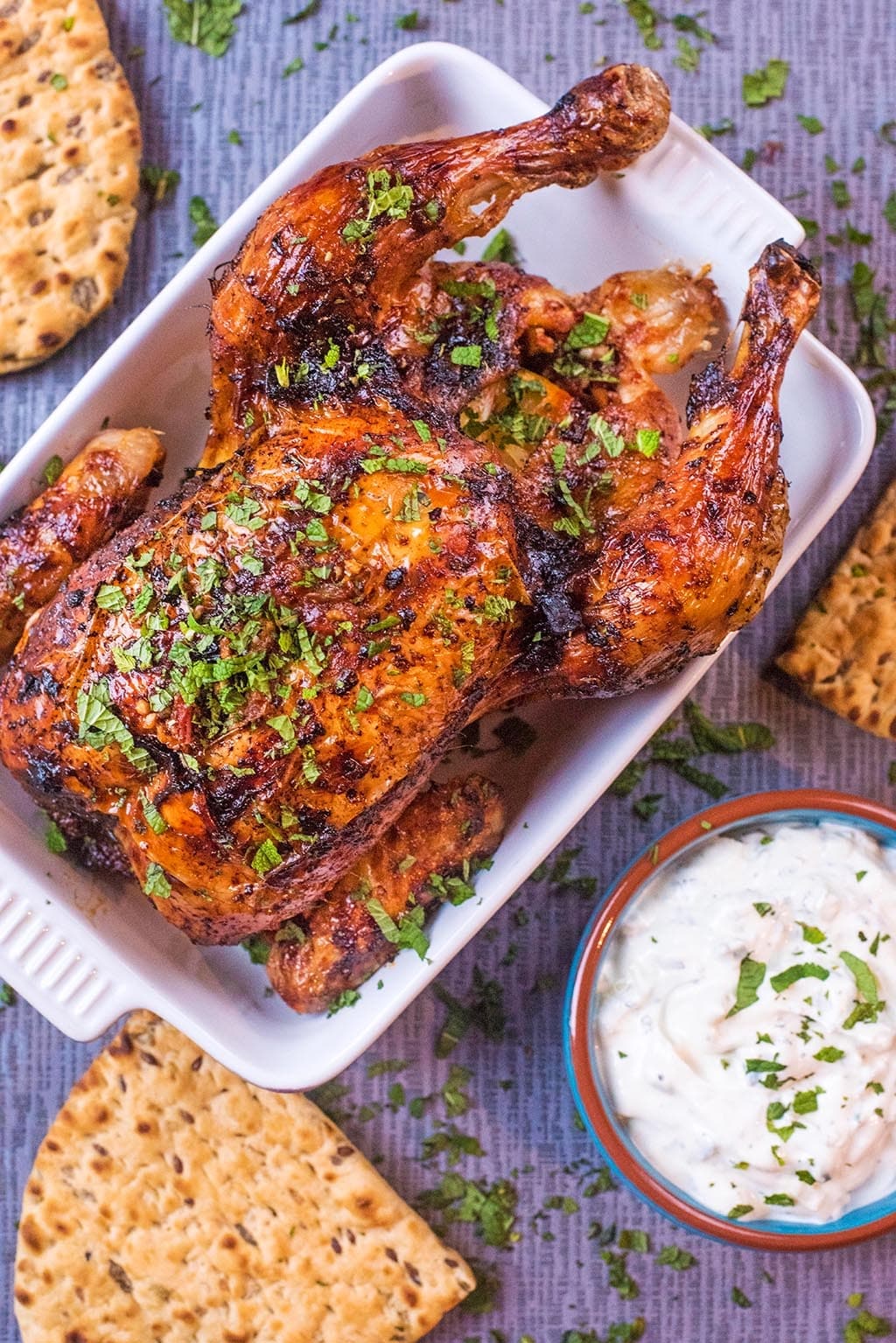 Roasted Harissa Chicken in a baking dish next to flatbreads and dip.