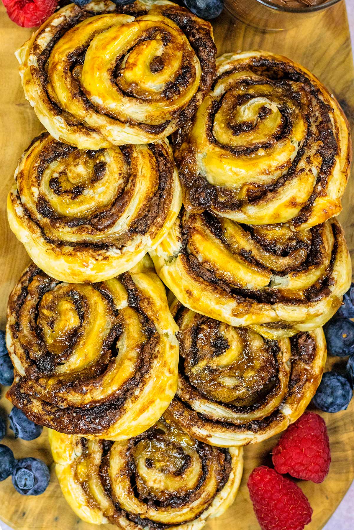 Chocolate pinwheels piled up surrounded by berries.