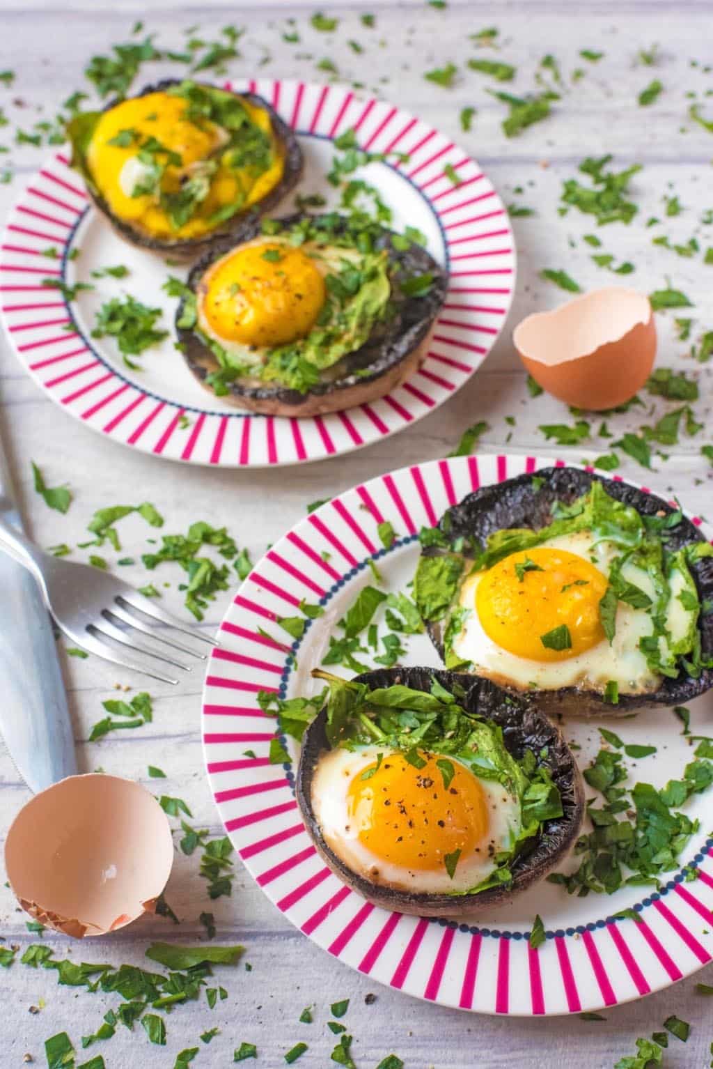 Two plates each with two Portobello Mushrooms with eggs in them.