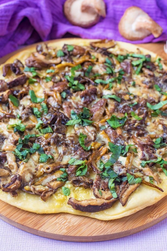 A Garlic Mushroom Pizza on a wooden serving board