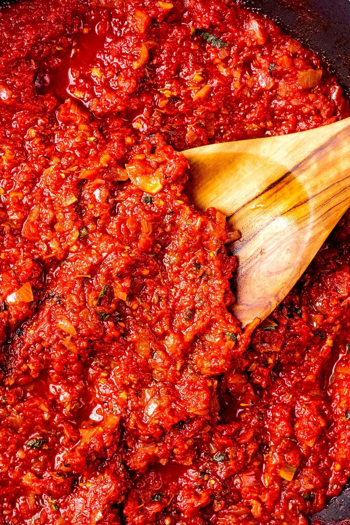 A wooden spoon in some marinara.