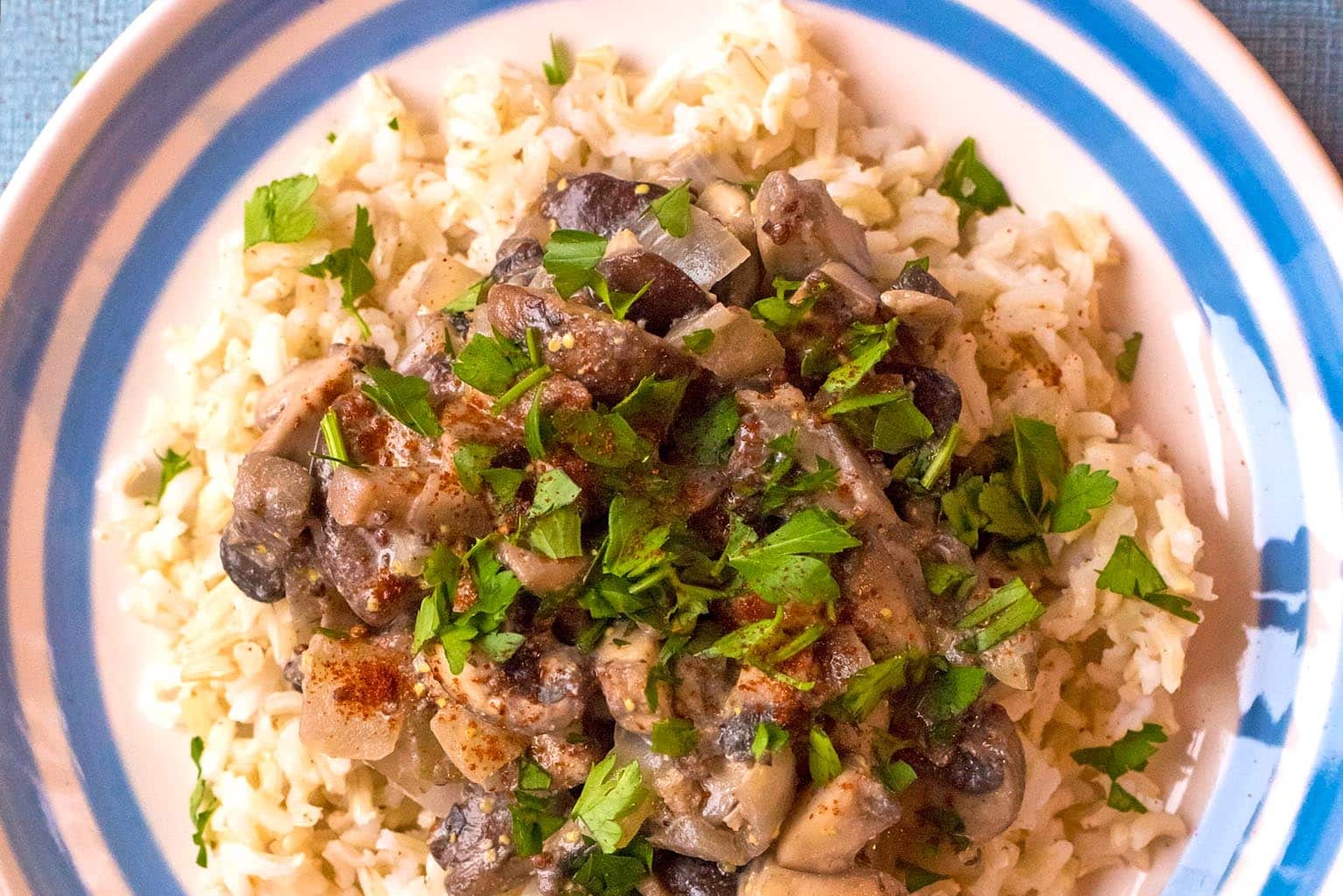 Mushroom Stroganoff on a blue and white plate with chopped parsley sprinkled on top.