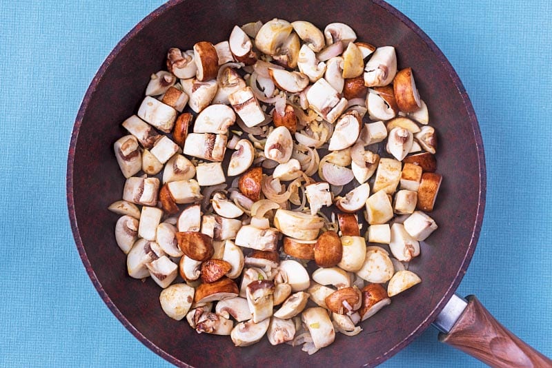 Chopped mushrooms and shallots in a frying pan.