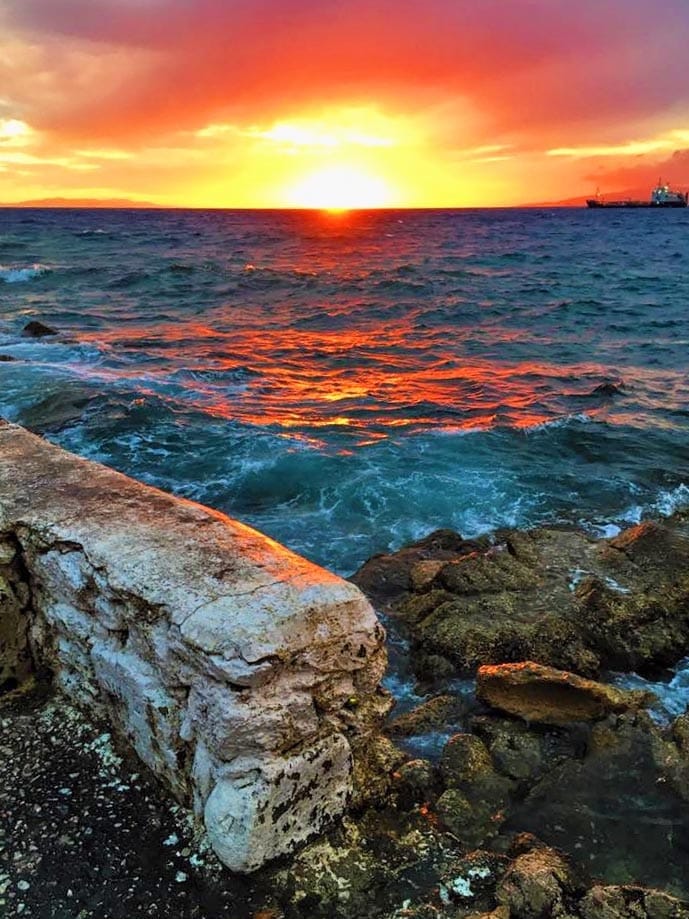 Sunset over a the sea with a wall in the foreground.