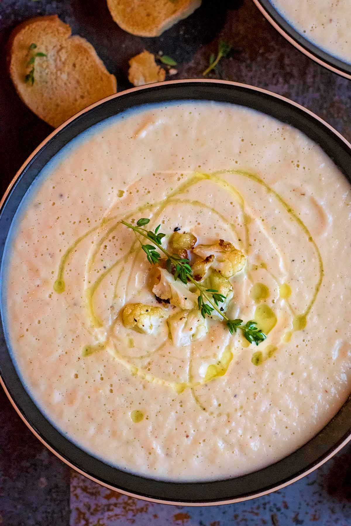 Cauliflower soup topped with sprigs of thyme, tiny cauliflower florets and a drizzle of oil.