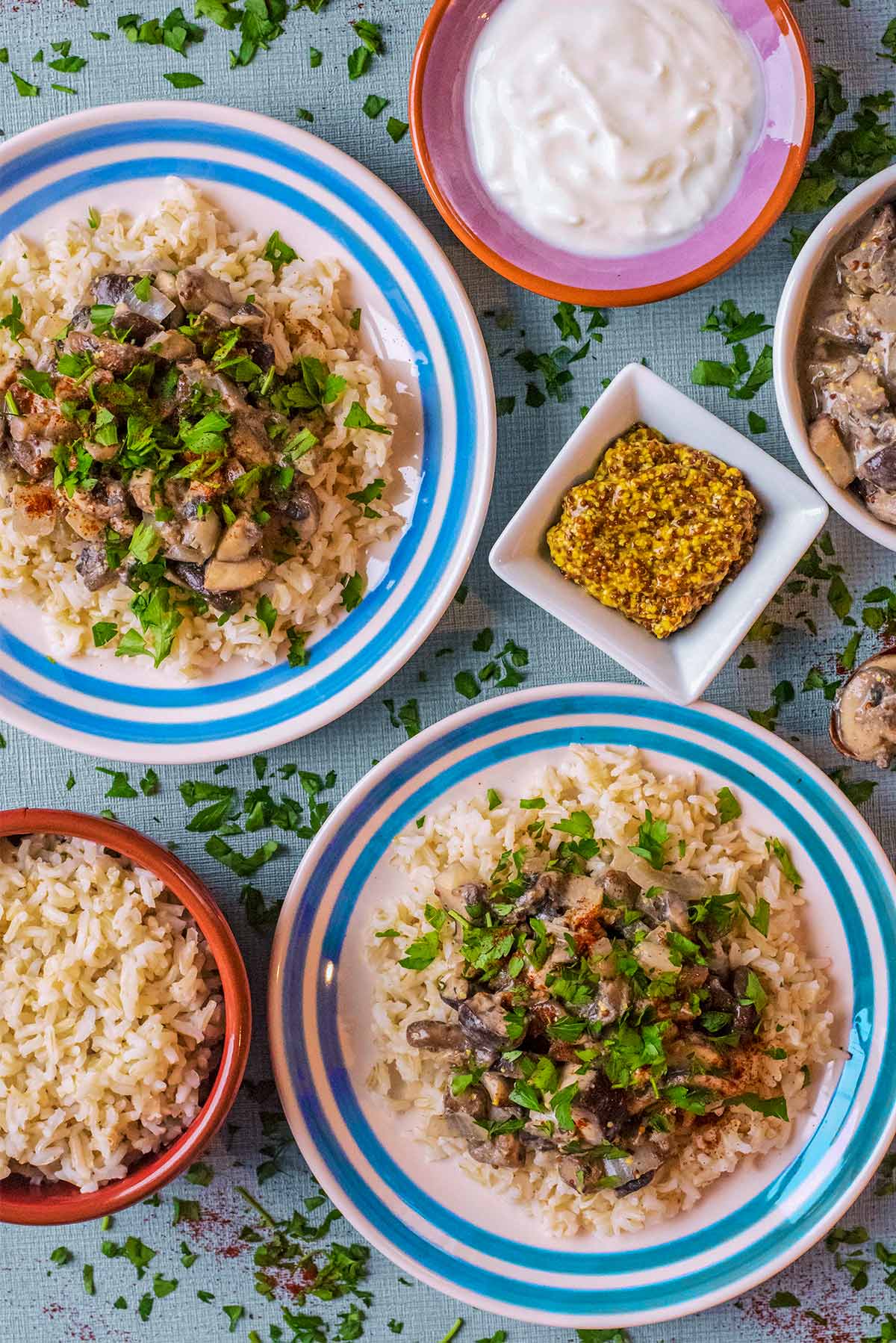 Two plates of Mushroom Stroganoff next to a small pot of mustard.