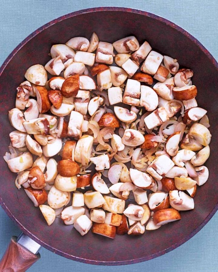 Chopped mushrooms and shallots in a frying pan.