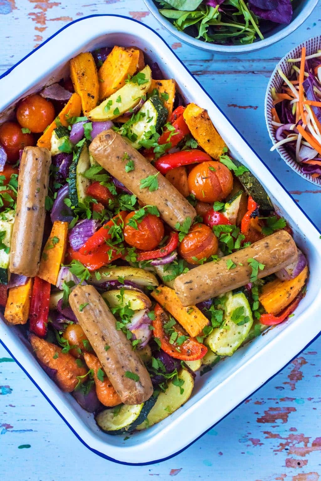 Sausages and chopped vegetables in a baking tray.