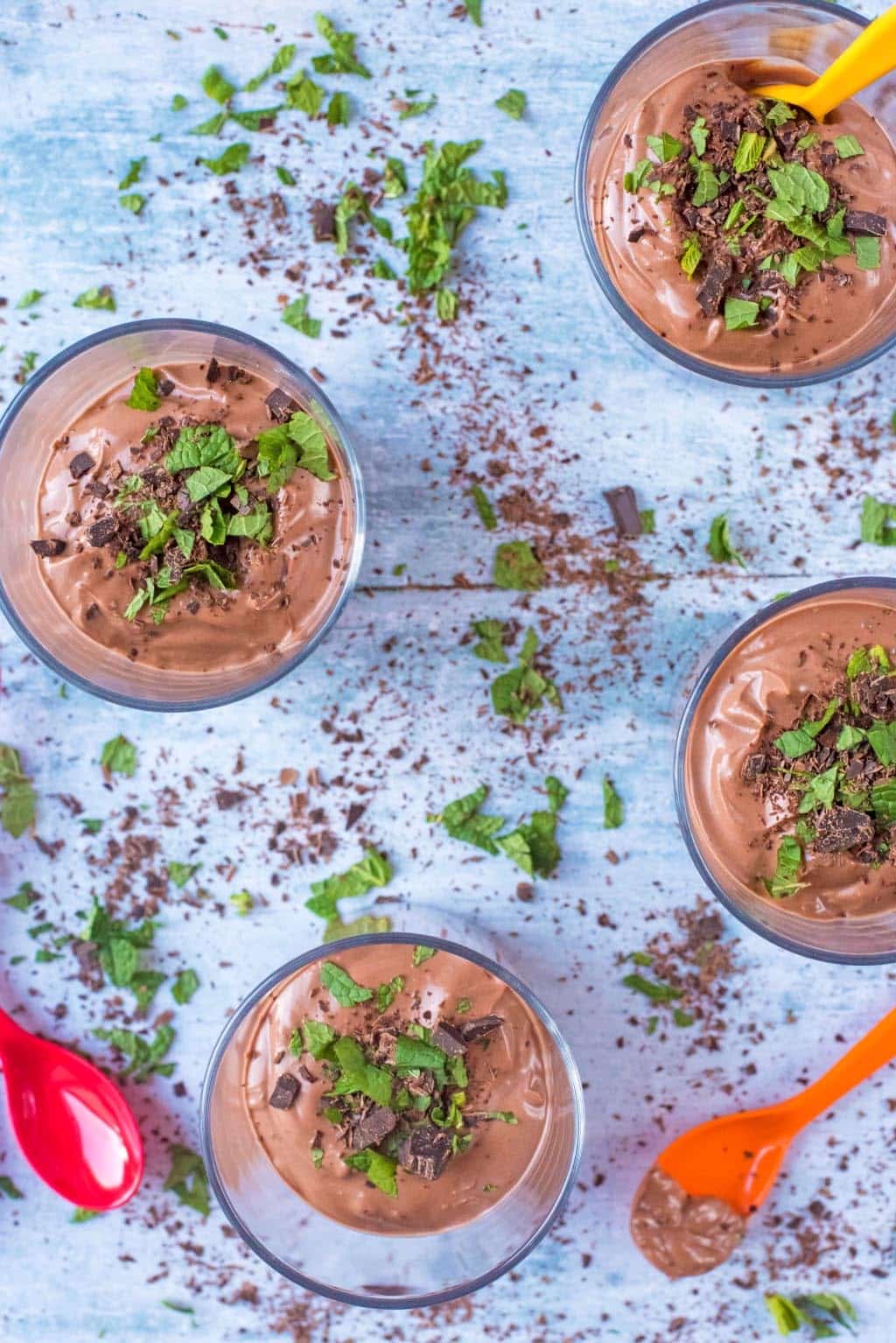 Four chocolate desserts topped with chocolate chunks and chopped mint leaves.
