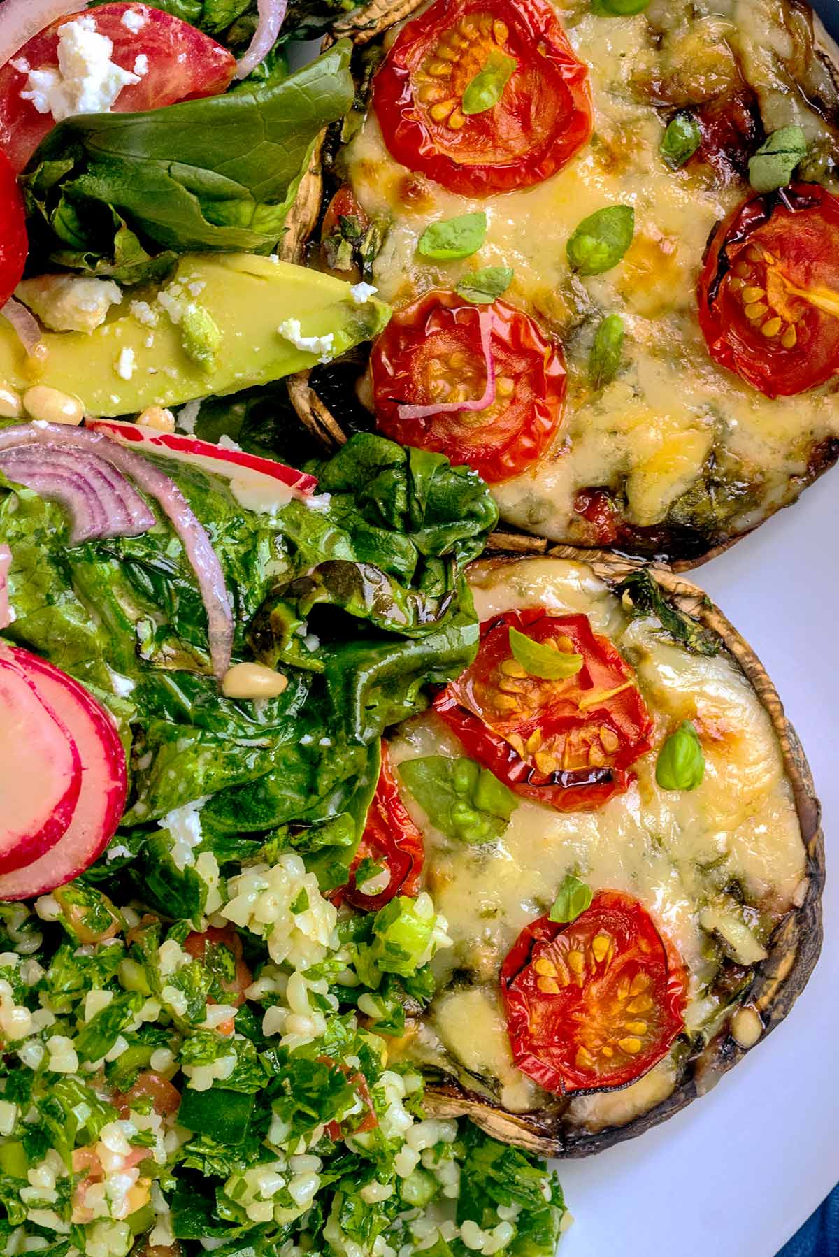 Two mushroom pizzas on a plate with some tabbouleh salad.