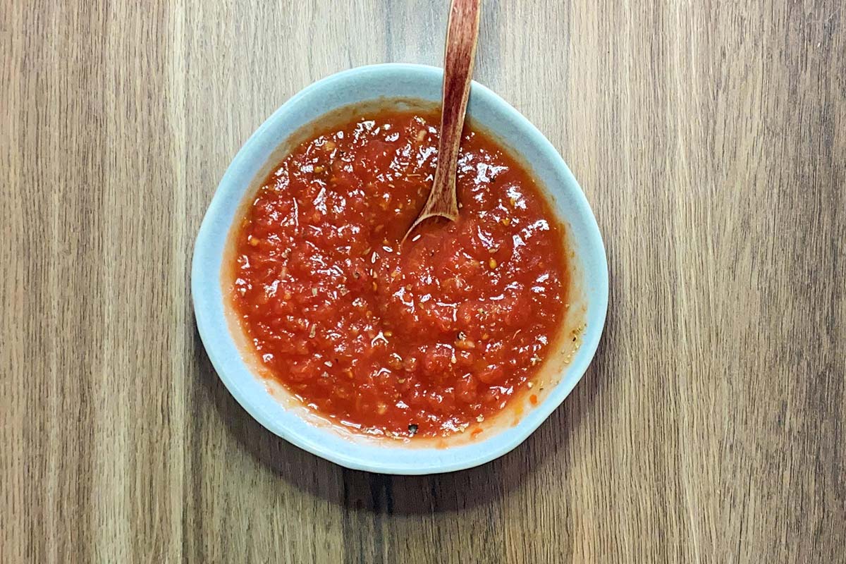 A small bowl containing a pizza sauce.