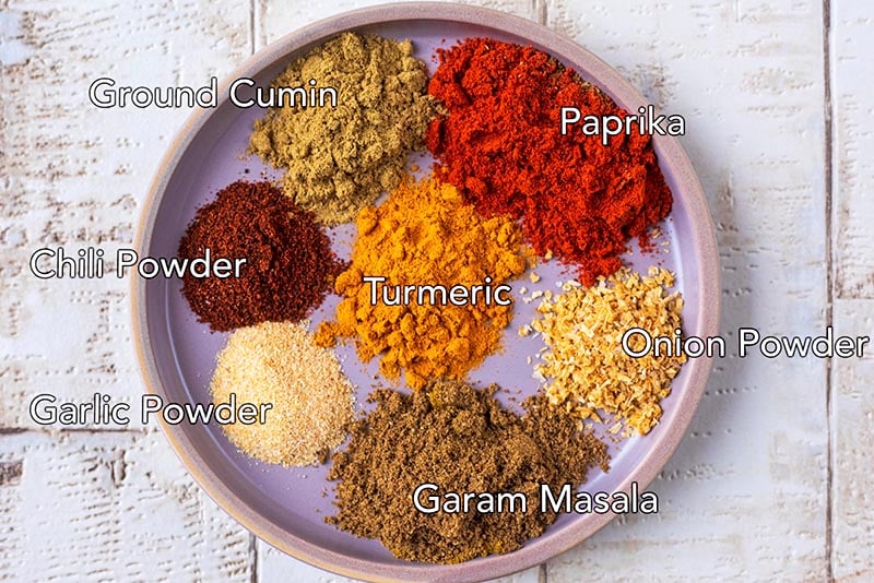 A plate with seven spices. Each spice is labelled with a text overlay.