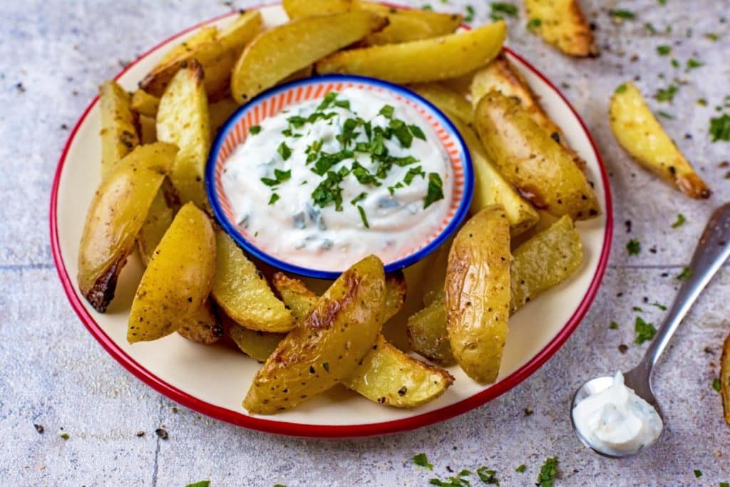 Cooked wedges on a white plate with a small bowl of dip.