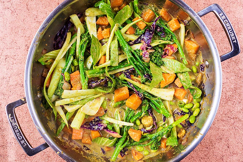A large pan with vegetables cooking in a Thai green sauce.