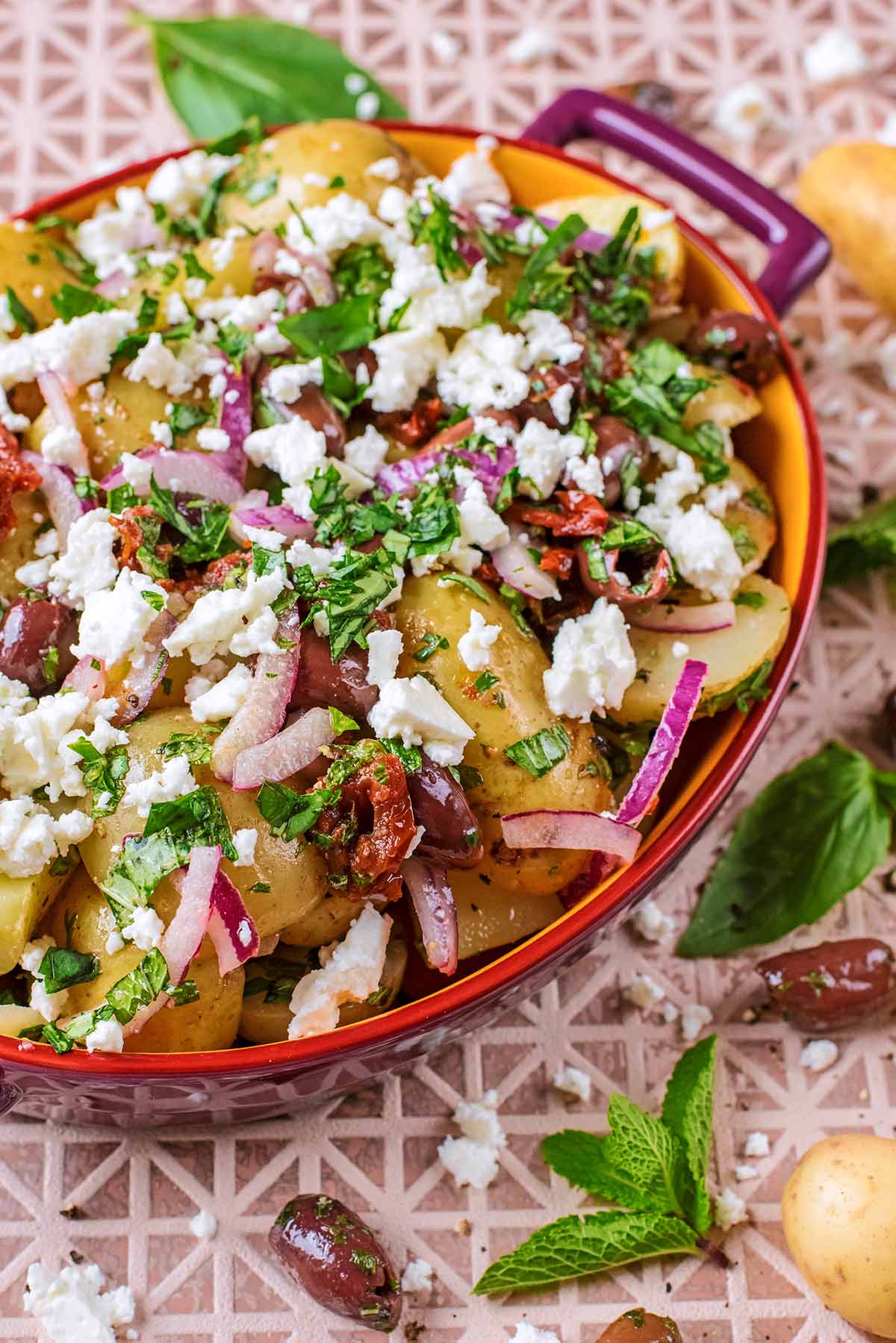 Potato Salad in an oval bowl topped with herbs and feta.