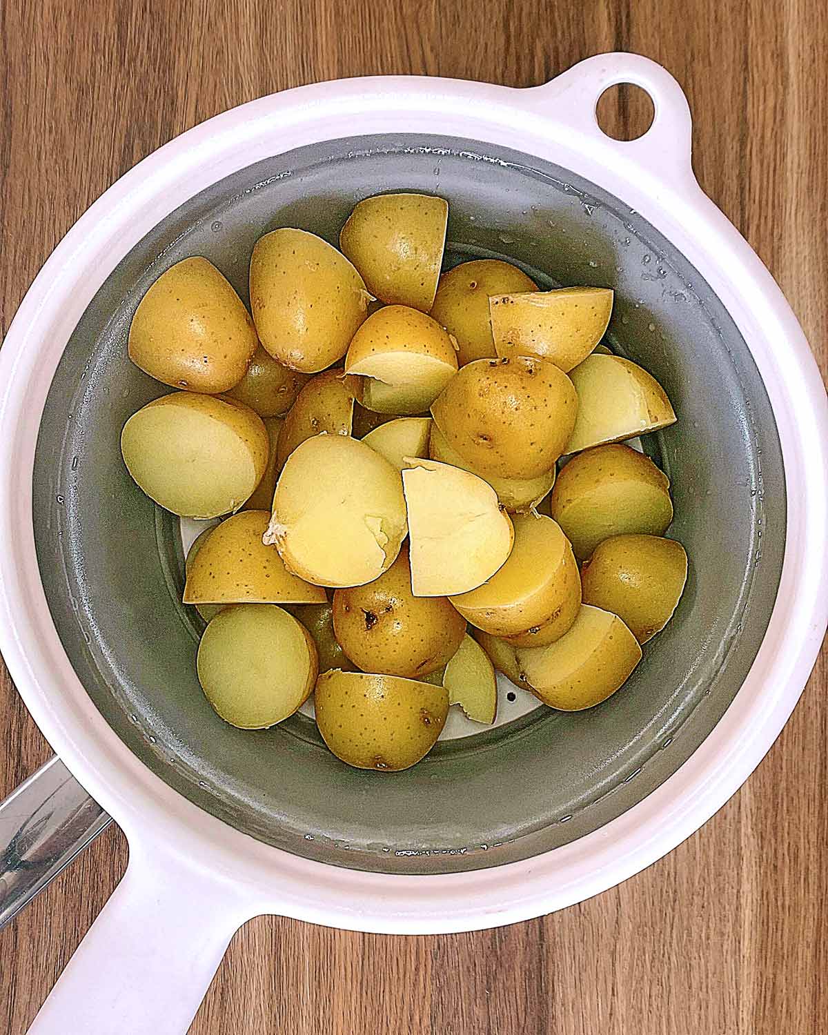 Cooked baby potatoes steam drying in a colander.