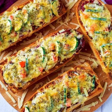 Four slices of French Bread Pizza on a wooden serving board.