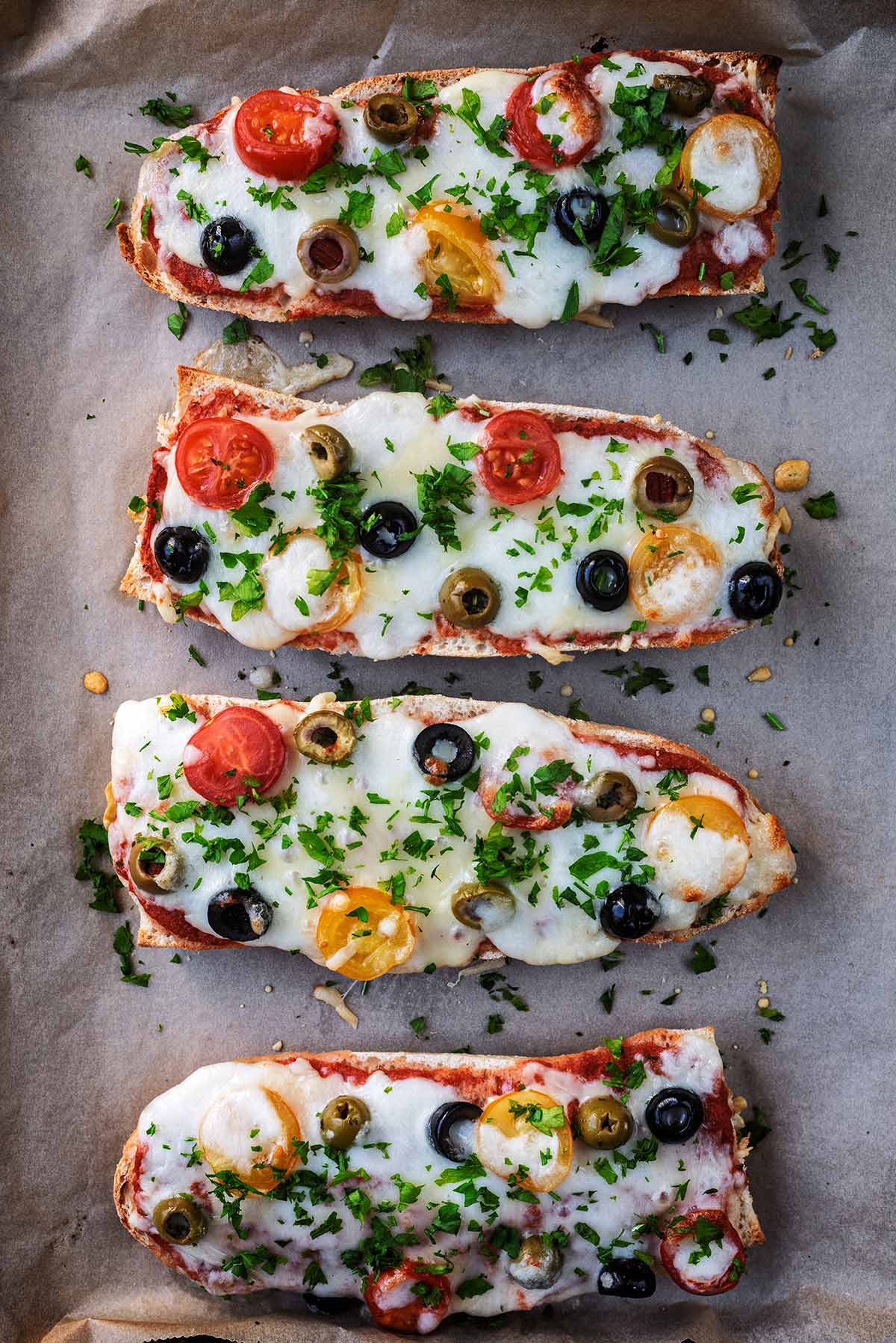 Four slices of long, thin pizza on a sheet of baking paper.