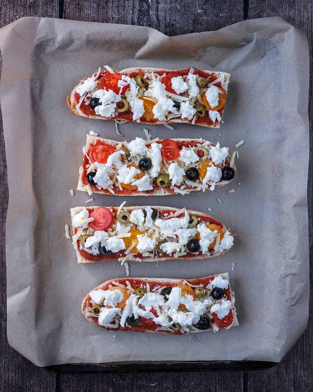 Sliced olives, halved cherry tomatoes and torn Mozzarella on top of the cheddar.
