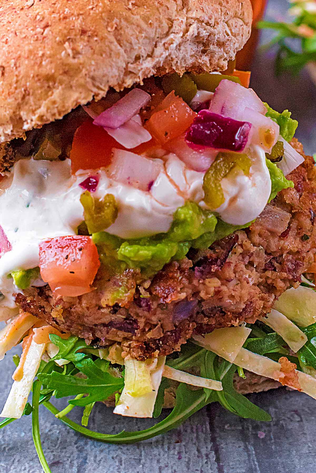 A bean burger in a bun topped with slaw and guacamole.