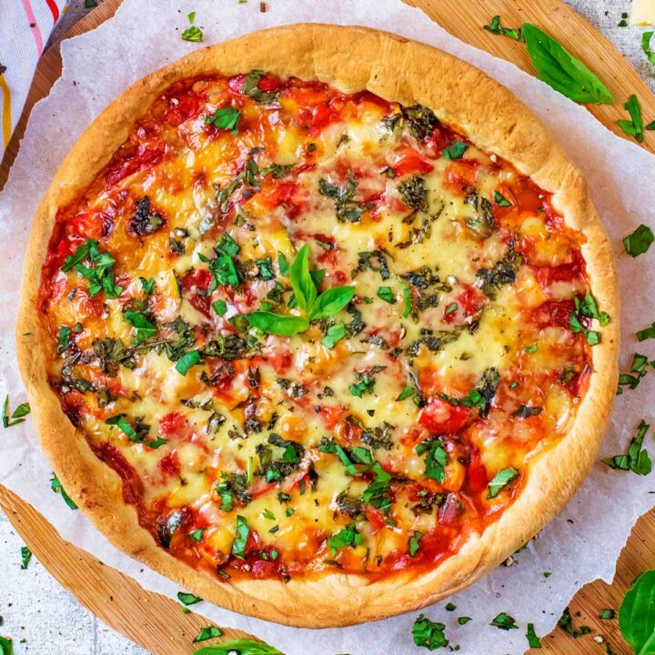 Chicago Deep Dish Pizza on a serving board surrounded by basil.