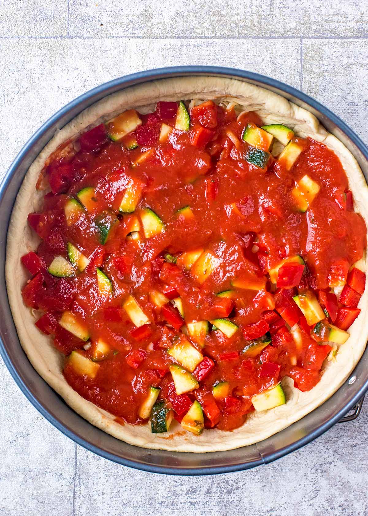 Deep Dish Pizza tin with vegetables and sauce.