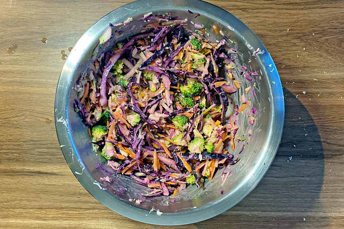 A bowl of slaw mixed together with dressing.
