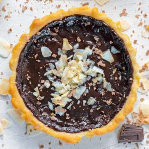 Chocolate Pie topped with coconut flakes and surrounded by chunks of chocolate.